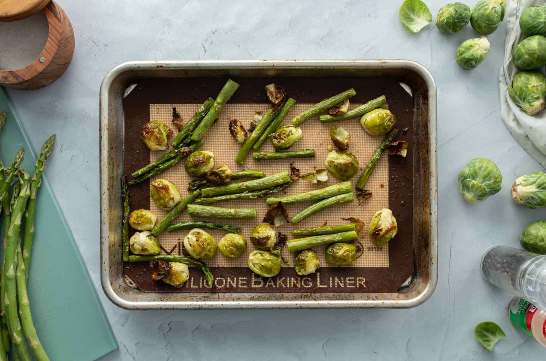 roasted brussels sprouts halves and asparagus on pan