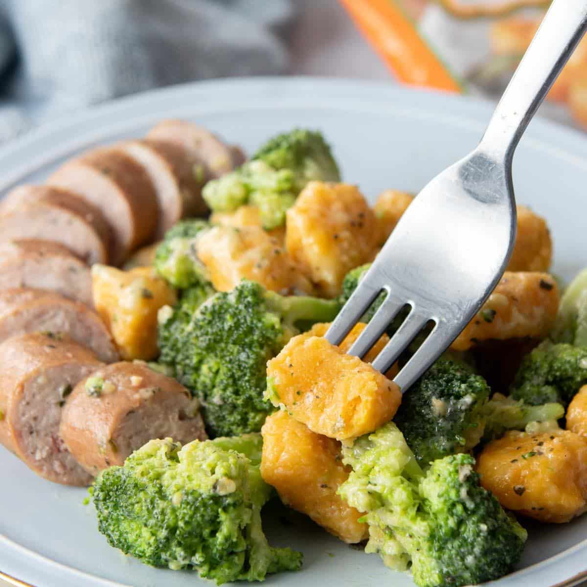 cut piece of sweet potato gnocchi on fork with food behind it