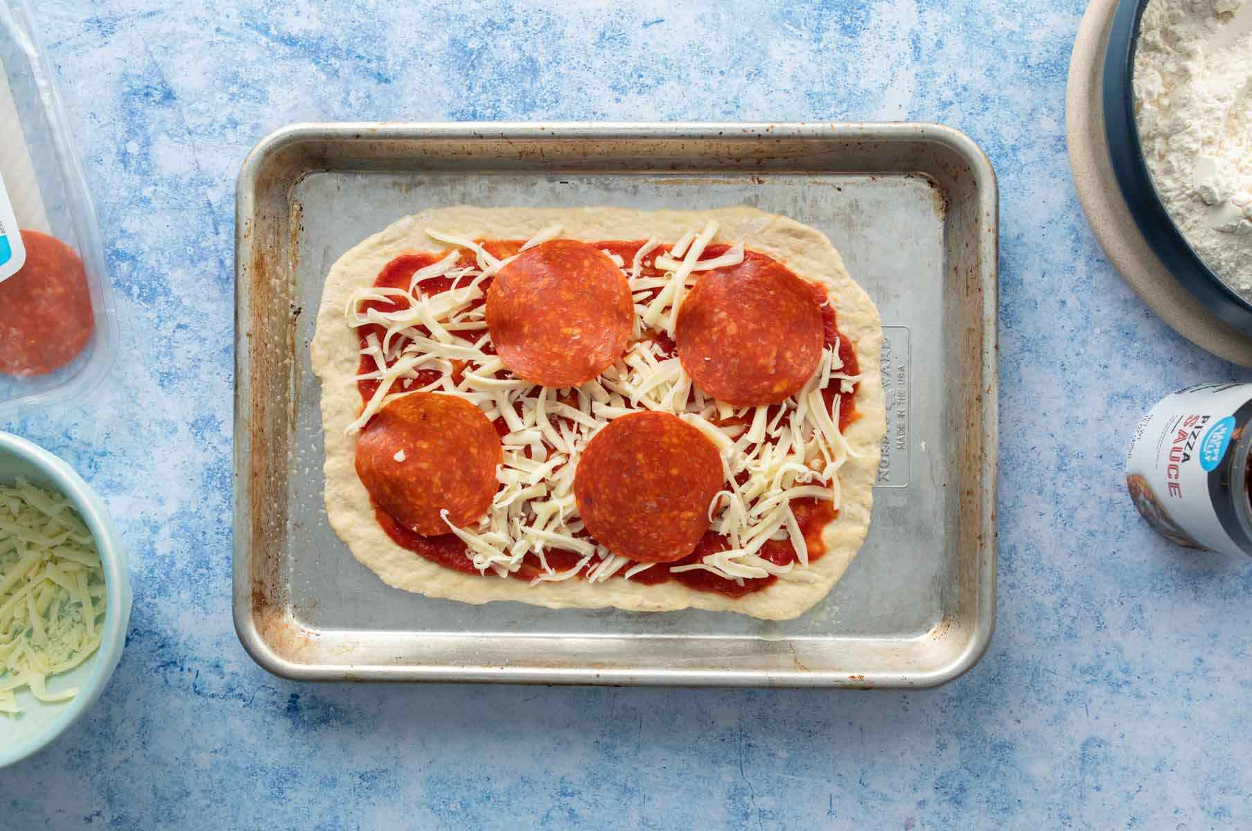 uncooked rectangular pepperoni pizza on pan